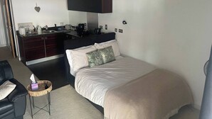Een slaapkamer met een bed, nachtkastje en een bureau met een stoel.
