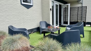 A patio with two chairs, a small table, and a potted plant.