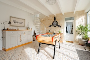 A room with a foosball table, a staircase, a clock, and a welcome sign.