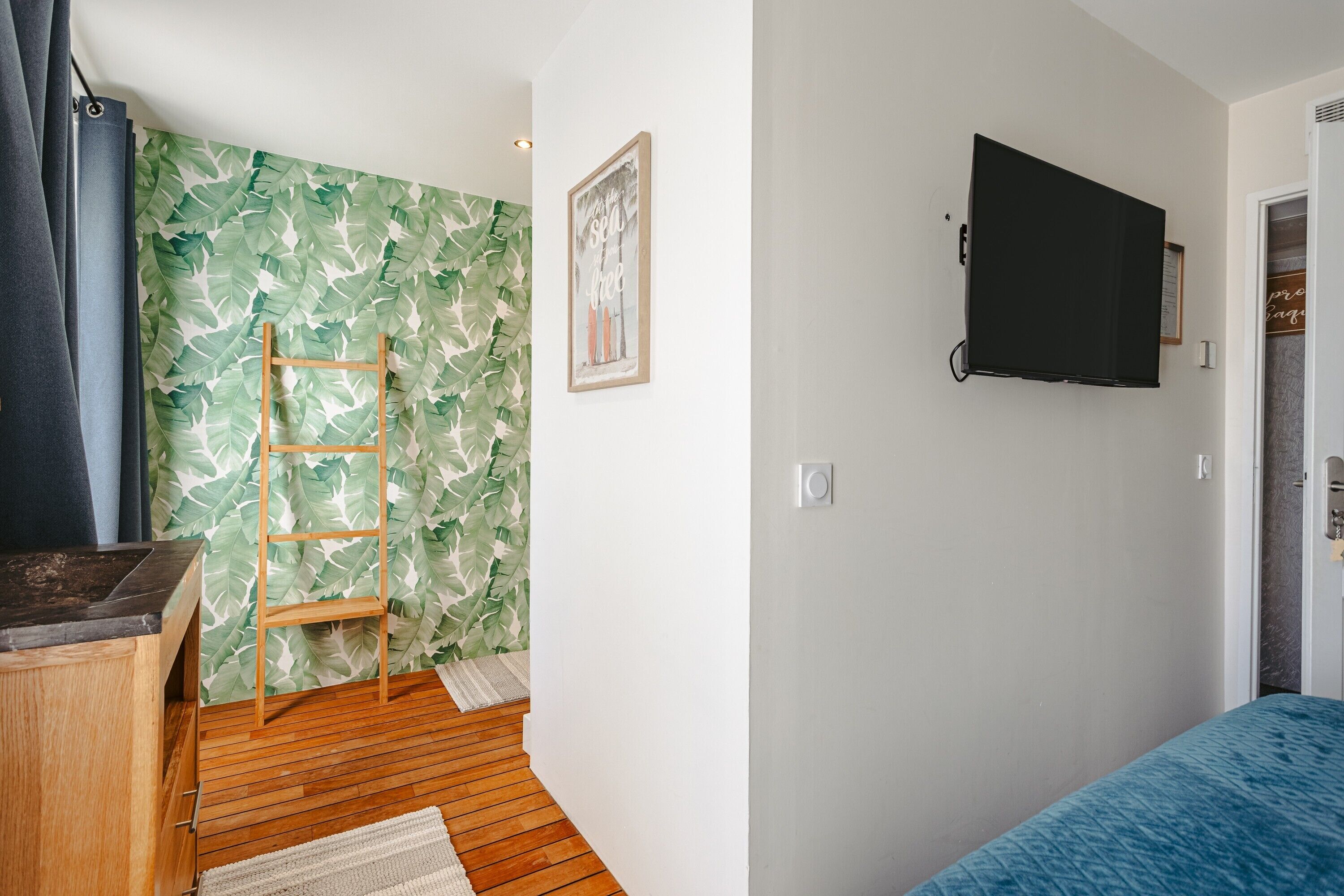 Ein Zimmer mit Holzboden, einem an der Wand montierten Fernseher, einer Himmelsleiter und einem gerahmten Bild.
