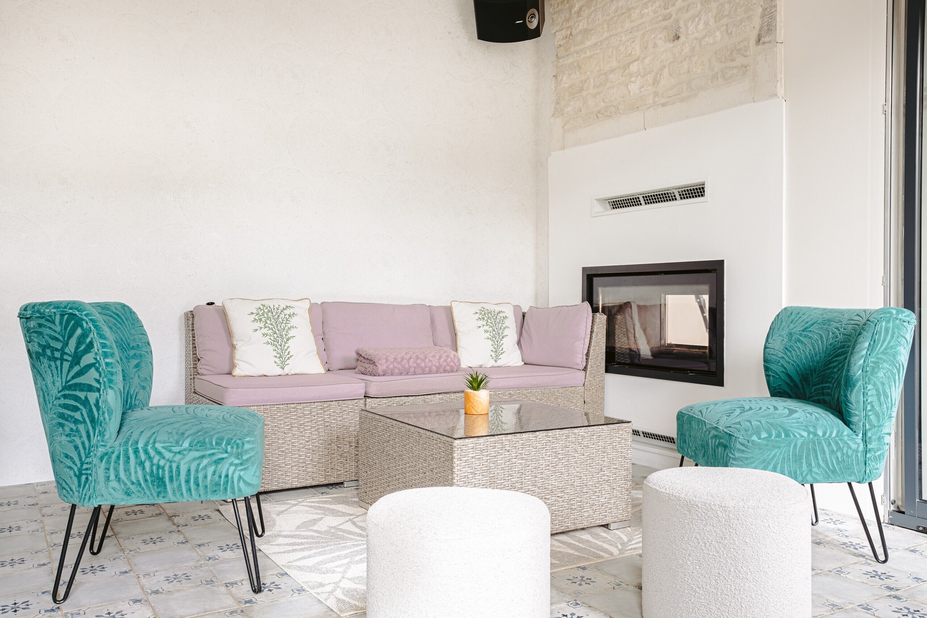 Una stanza con un divano, due poltrone, un tavolino in vetro e un pouf bianco.