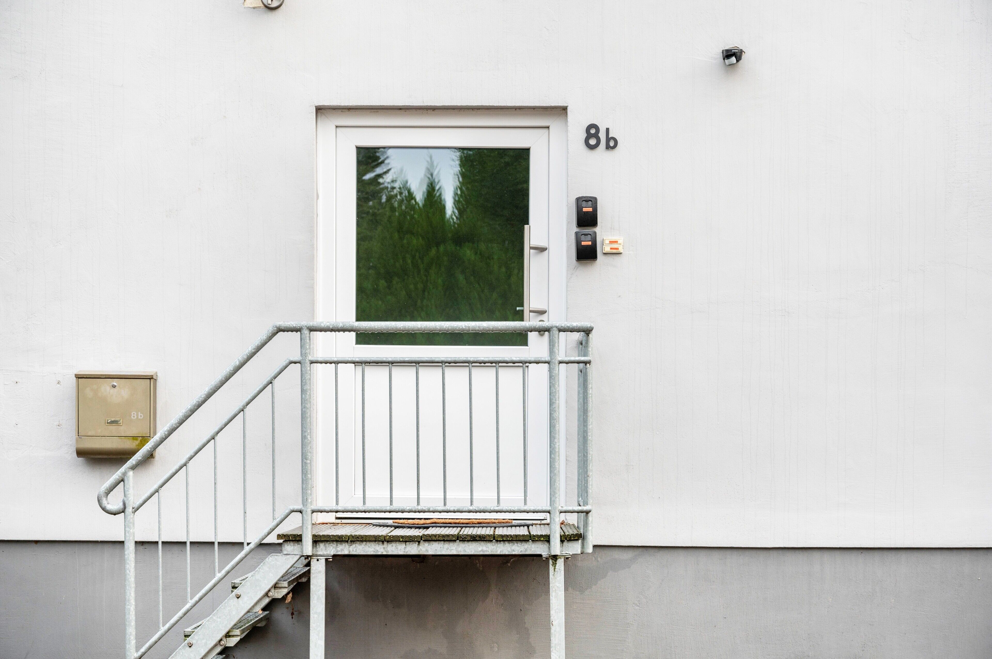 A white building with a door marked '8b' and a small outdoor staircase leading to a balcony.
