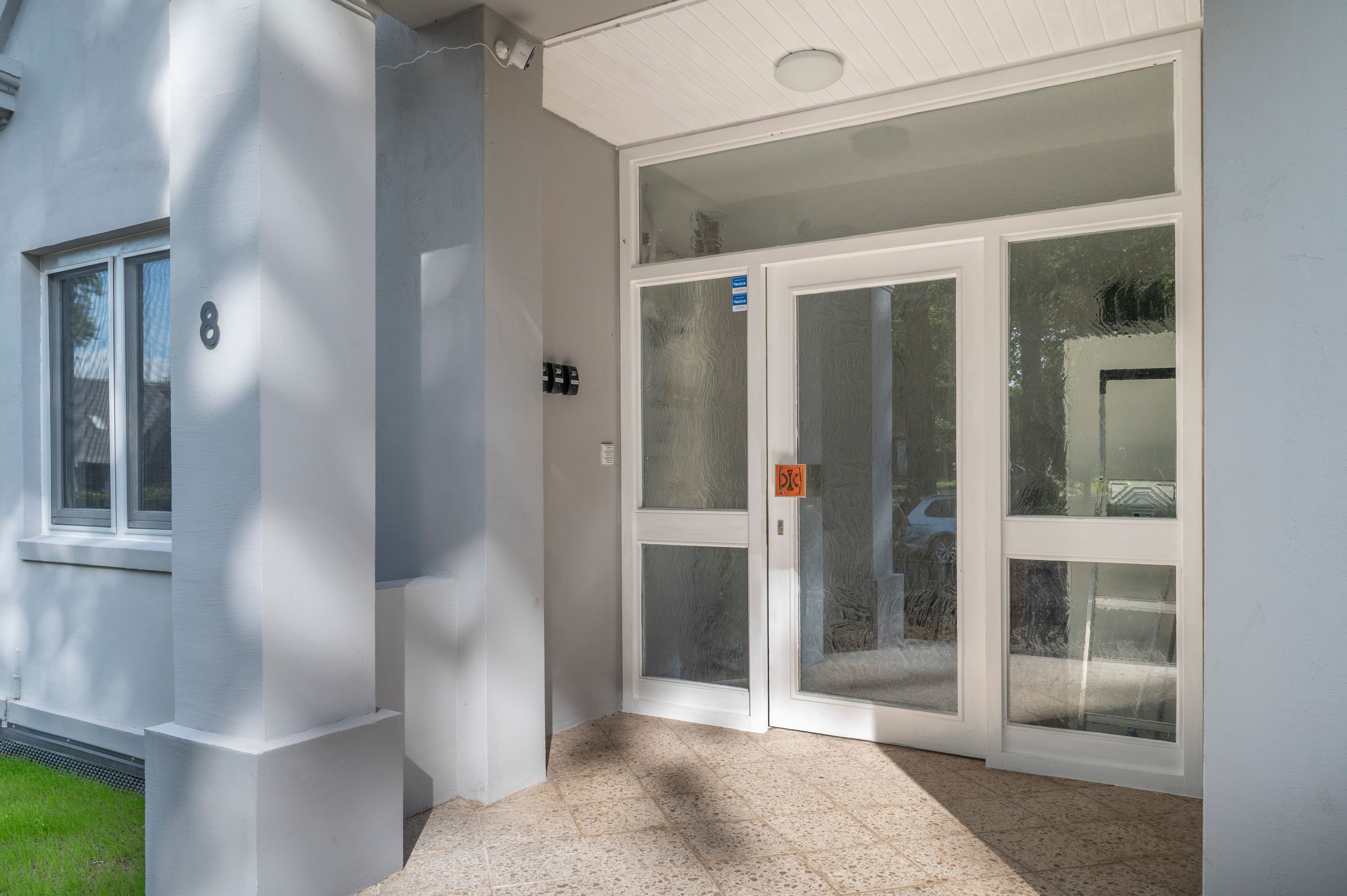 A building entrance with a double door, a small window, and a number '8' on the wall.