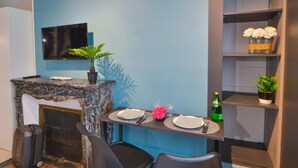 A compact dining area with a marble countertop, two black chairs, a small potted plant, and a bottle of champagne. - puits de jouvence (Bourges)