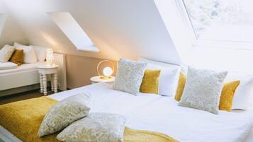 Ein Hotelzimmer mit Bett, Kissen, einem Nachttisch mit Lampe und einem Fenster.