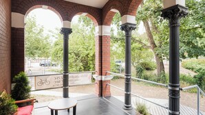 An outdoor patio with brick arches, a metal railing, and a sign indicating a bike rental service. - Johanniter Hotel Wittenberg (Lutherstadt Wittenberg)