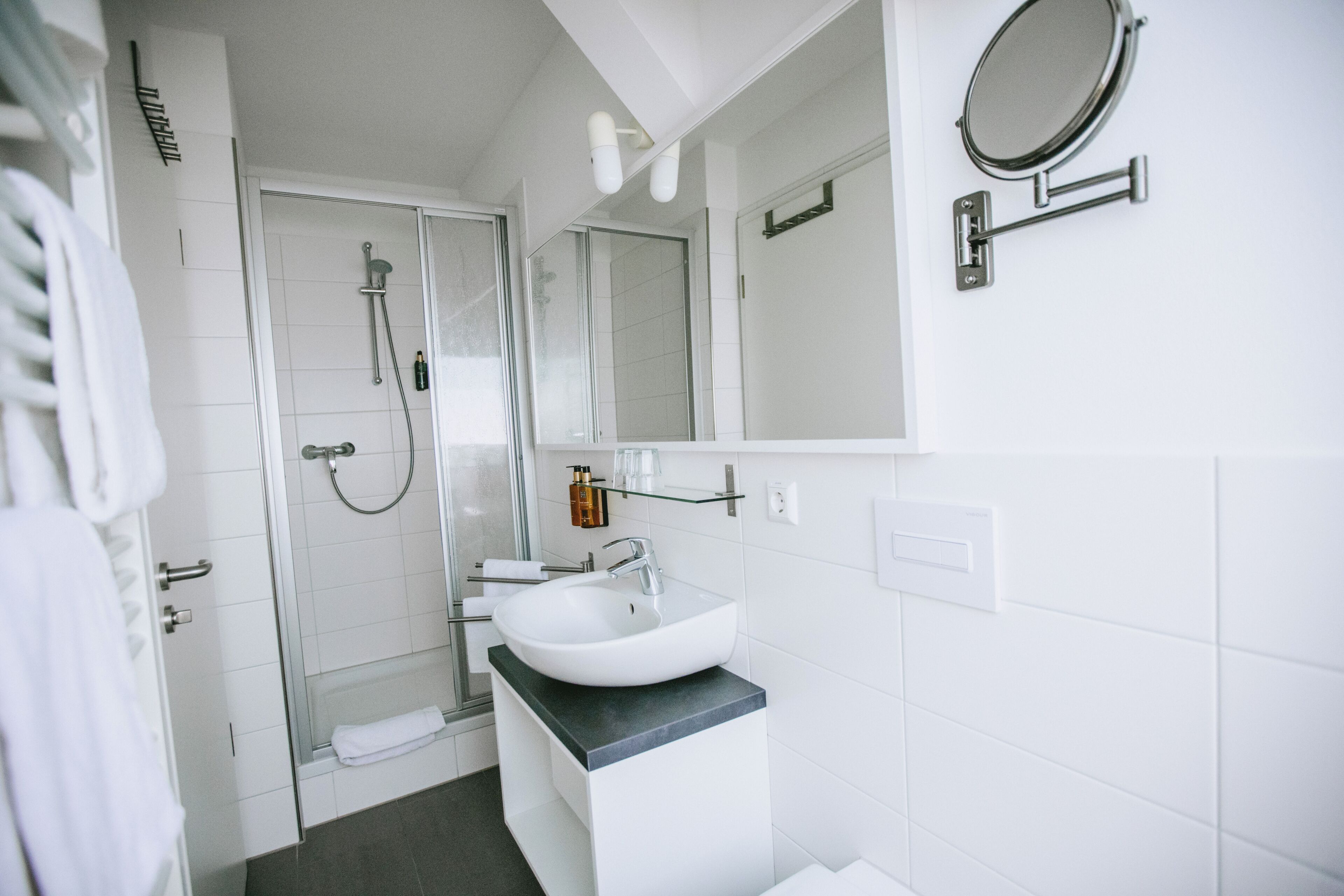 A modern bathroom with a white sink, a glass shower enclosure, and a mirror.