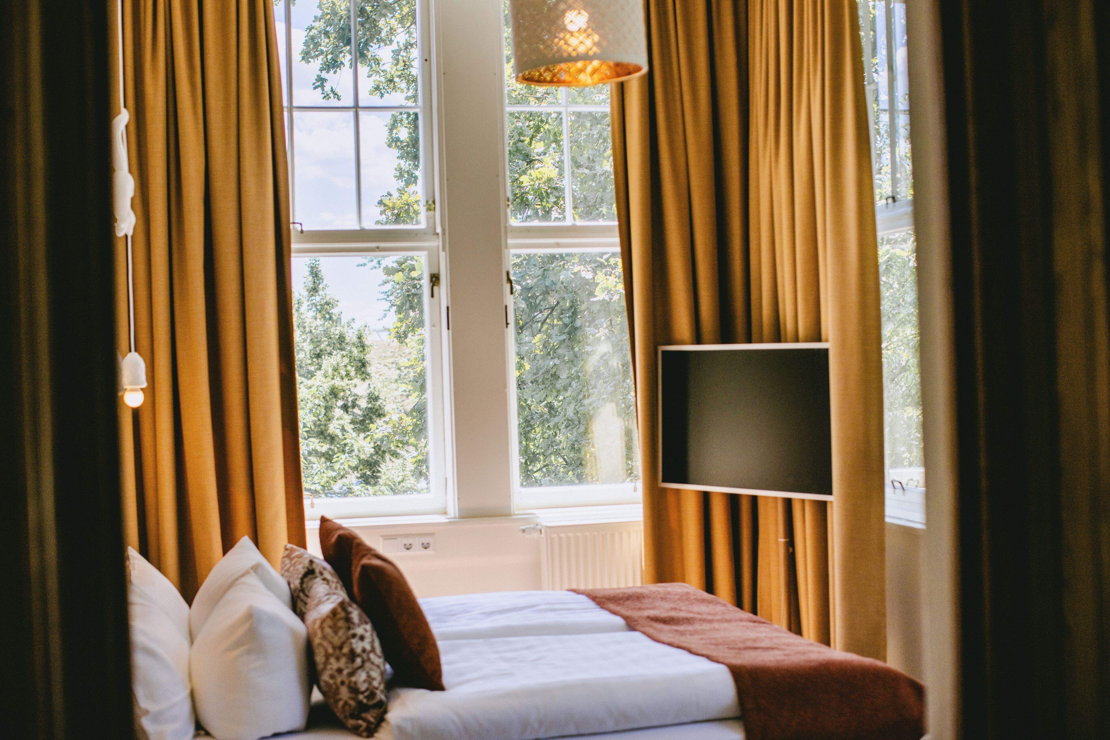 A bedroom with a bed, a TV, and curtains.