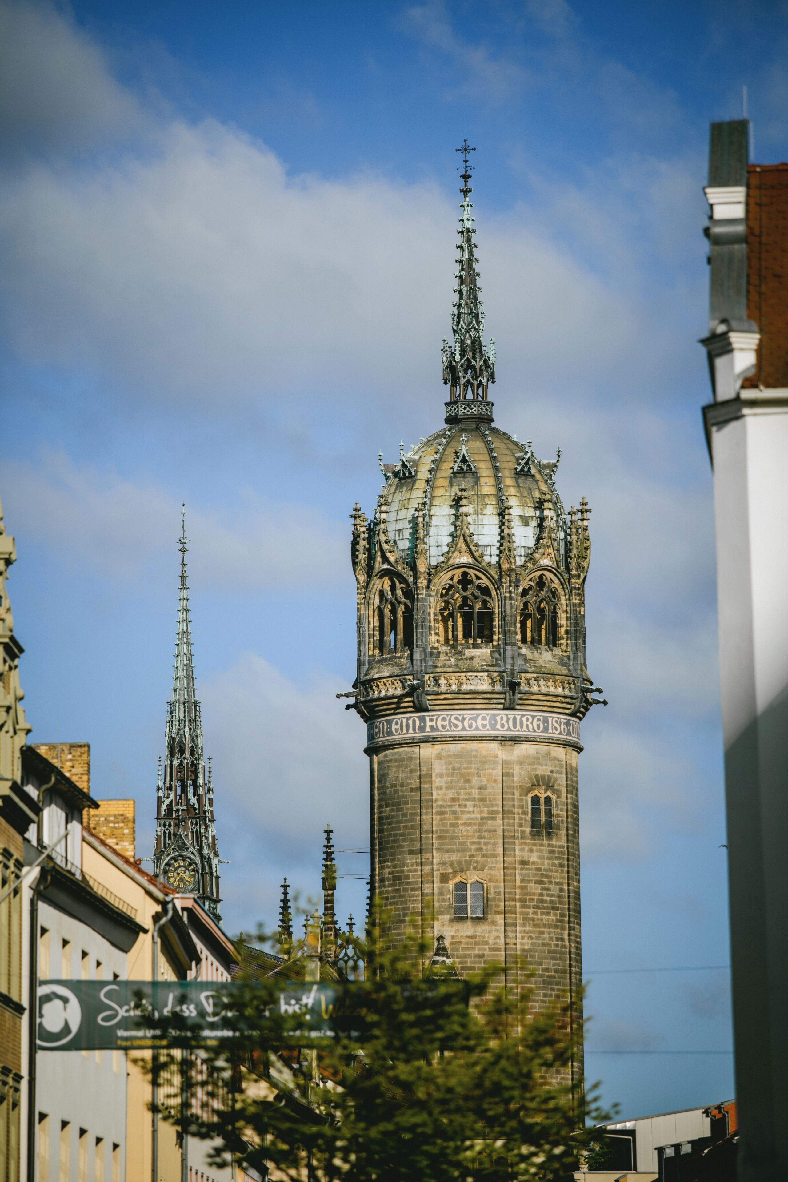 Una torre histórica con detalles arquitectónicos intrincados y una cúpula, rodeada de edificios modernos.