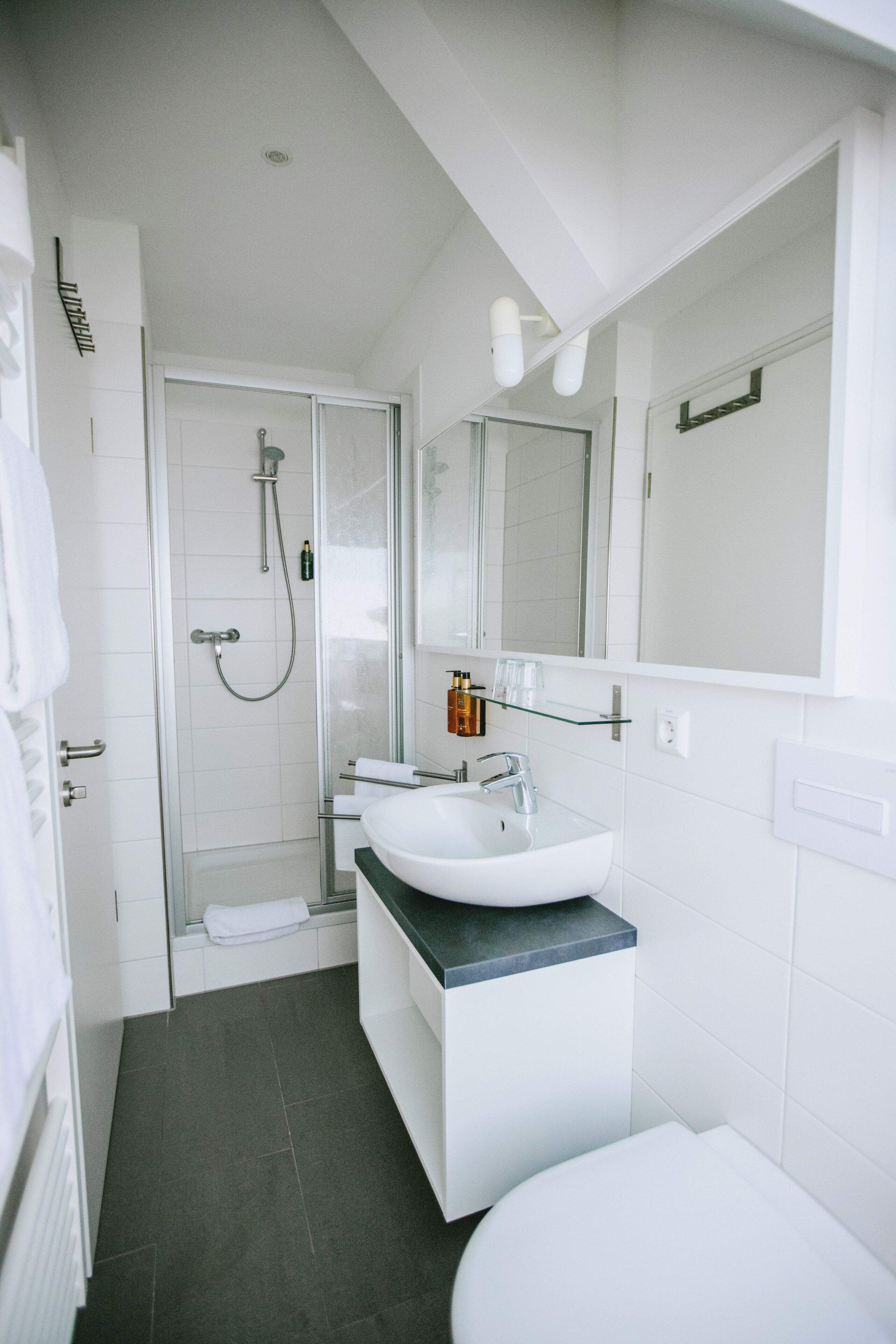 A modern bathroom with a glass shower enclosure, a white sink, and a large mirror.