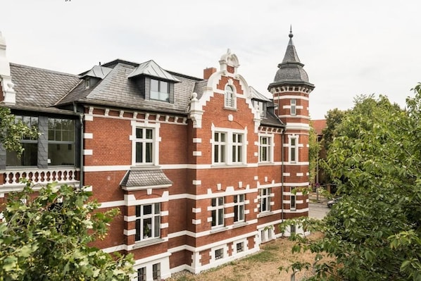 A large, red brick building with white trim and a tower.