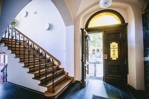 Una escalera de madera con barandillas negras que lleva a una puerta con un panel de vidrio.