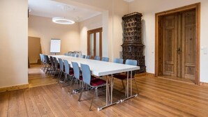 A conference room with a long table, blue chairs, and a wooden cabinet. - Johanniter Hotel Wittenberg (Lutherstadt Wittenberg)