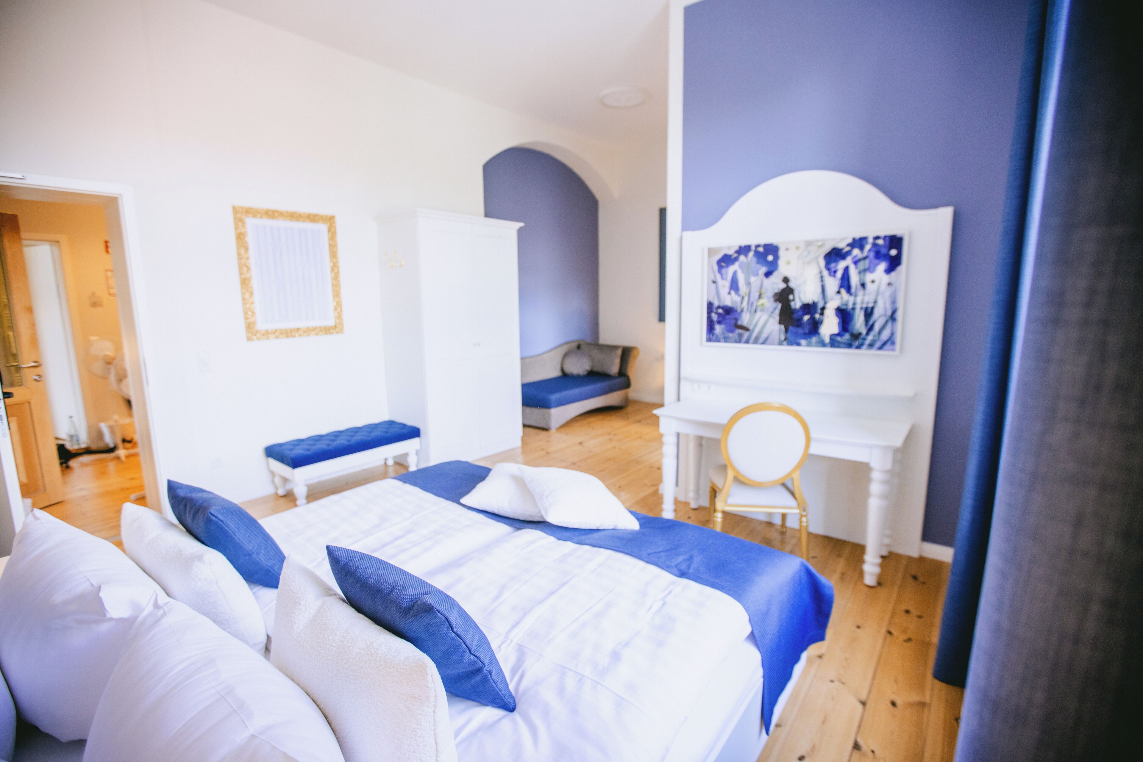 Une chambre à coucher avec un lit, un bureau, une chaise et un tableau accroché au mur.