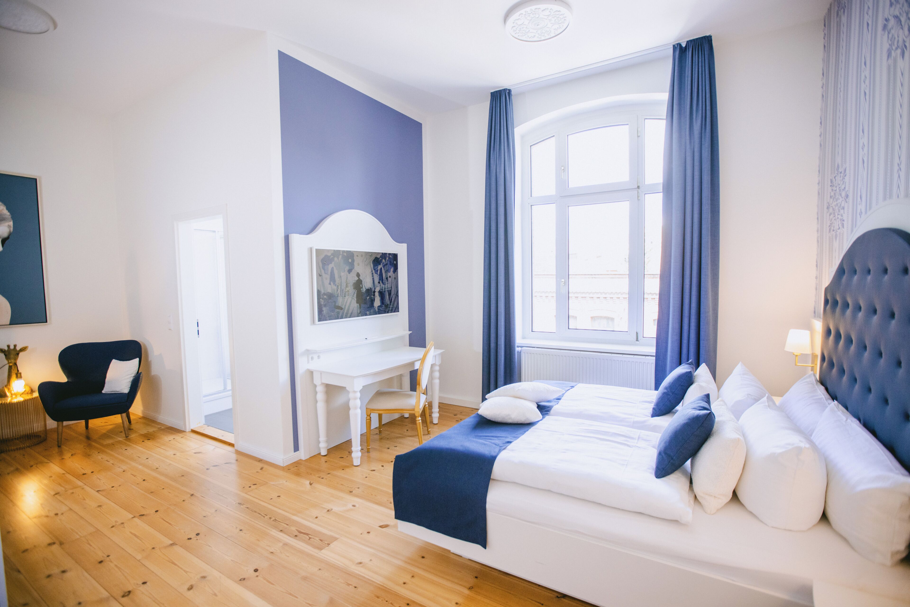 Une chambre à coucher avec un lit, un bureau, une chaise et une fenêtre avec des rideaux.