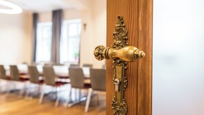 A wooden door with an ornate brass handle, leading into a room with a long table and chairs. - Johanniter Hotel Wittenberg (Lutherstadt Wittenberg)