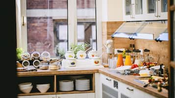 Een keuken met een raam, planken vol potten en een verscheidenheid aan keukengerei.