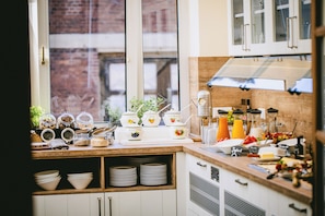 A kitchen with a window, shelves with jars, and a variety of kitchen utensils. - Johanniter Hotel Wittenberg (Lutherstadt Wittenberg)