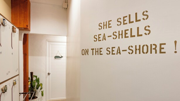 Un couloir avec une pancarte sur le mur indiquant : « Elle vend des coquillages au bord de la mer ! »