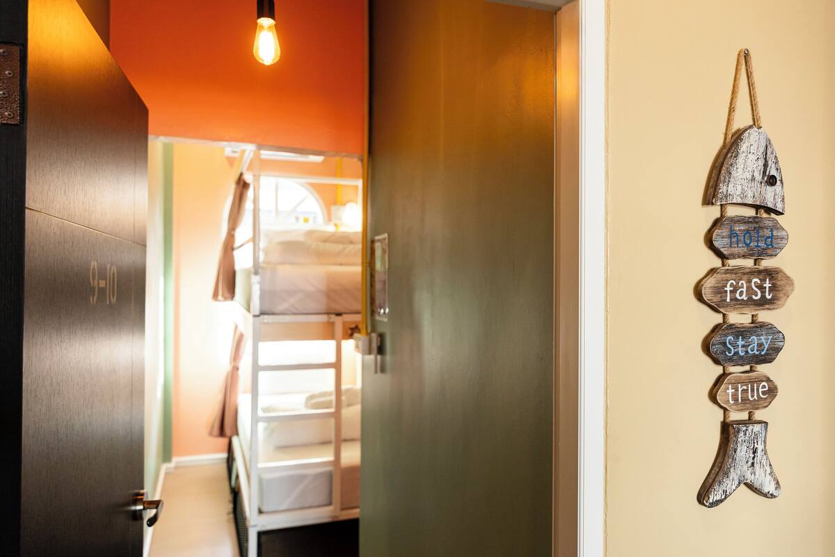 A hotel corridor with a bed, a wall with a motivational sign, and a door.