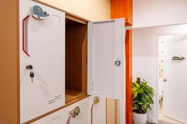 A room with a white cabinet, a potted plant, and a door labeled "RESTROOM". - Sweett Lemon Hostel (Patong)