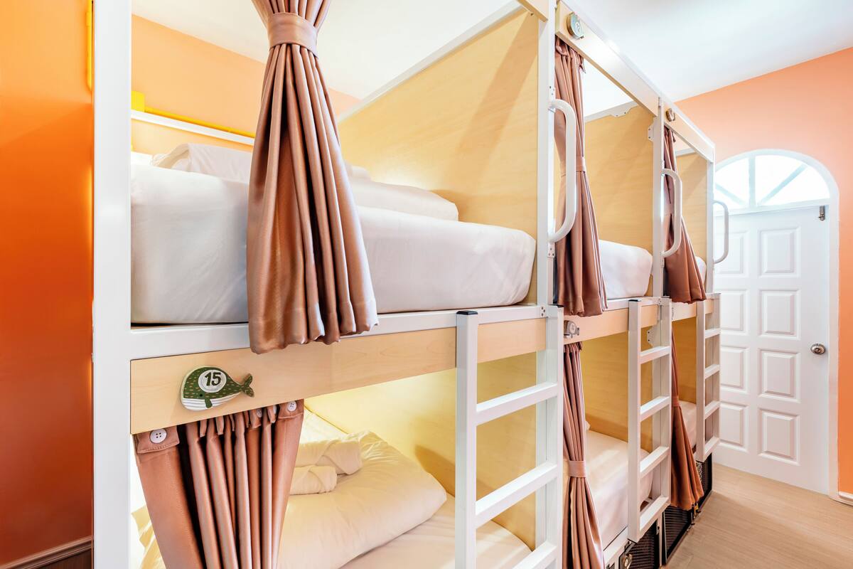 A bunk bed room with orange walls, a white door, and a small fish decoration on the lower bunk.