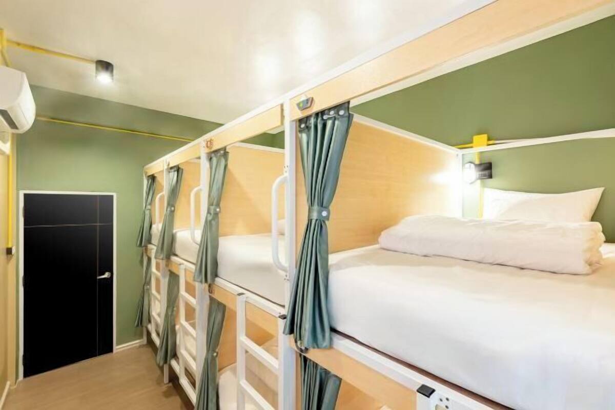 A bunk bed room with curtains, a door, and a light fixture.