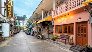 Une vue de rue avec, sur la droite, un bâtiment portant l’inscription « Sweet Lemon Hostel », avec une porte en bois et un banc à l’extérieur.