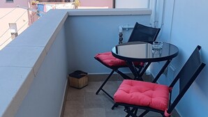 A small balcony with two black chairs and a table, a trash bin, and a window with a view of buildings. - ‘Tosca 5 L.T.I.’ Apartment with Balcony and Air Conditioning (Pisa)