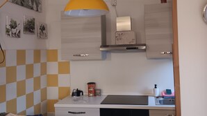 A kitchen with a yellow pendant light, a stove, a sink, and a microwave. - ‘Tosca 5 L.T.I.’ Apartment with Balcony and Air Conditioning (Pisa)