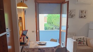 A dining area with a table, chairs, a laptop, and a window with blinds. - ‘Tosca 5 L.T.I.’ Apartment with Balcony and Air Conditioning (Pisa)