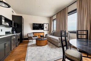 Una habitación de hotel moderna con cocina, un sofá, una mesita redonda y una mesa de comedor.