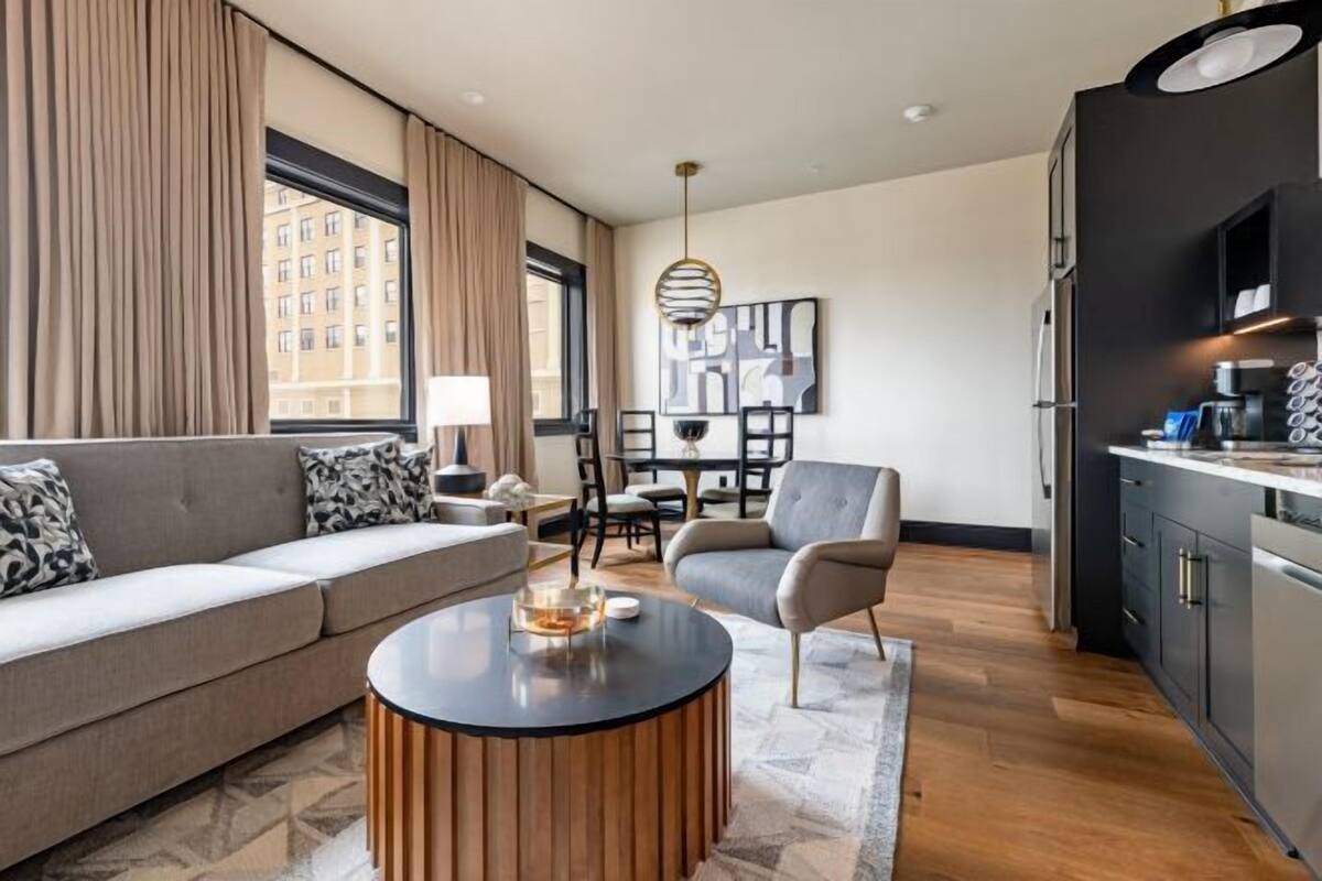 A modern living room with a sofa, a round coffee table, and a dining area with chairs and a table.