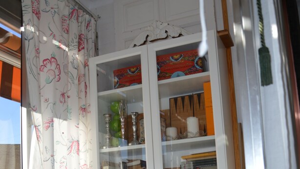 A dining area with a glass table, wicker chairs, a cabinet with glass doors, and a floral curtain. - Room in Sevilla (Santa Justa) (Sevilla)