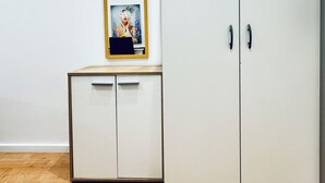A room with a white wardrobe, a small cabinet with a mirror, and wooden flooring. - Cozy 4BR Apartment Near Kaufpark (Vienna)