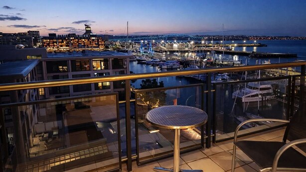 A balcony with a view of a marina and cityscape at dusk. - Modern Harbourside 1BR w Balcony Zodiak Stays (Auckland City)
