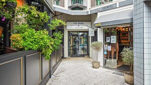 A hotel corridor with hanging plants, a sign for 'The Sebel Auckland,' and a giraffe statue outside a shop. - Modern Harbourside 1BR w Balcony Zodiak Stays (Auckland City)