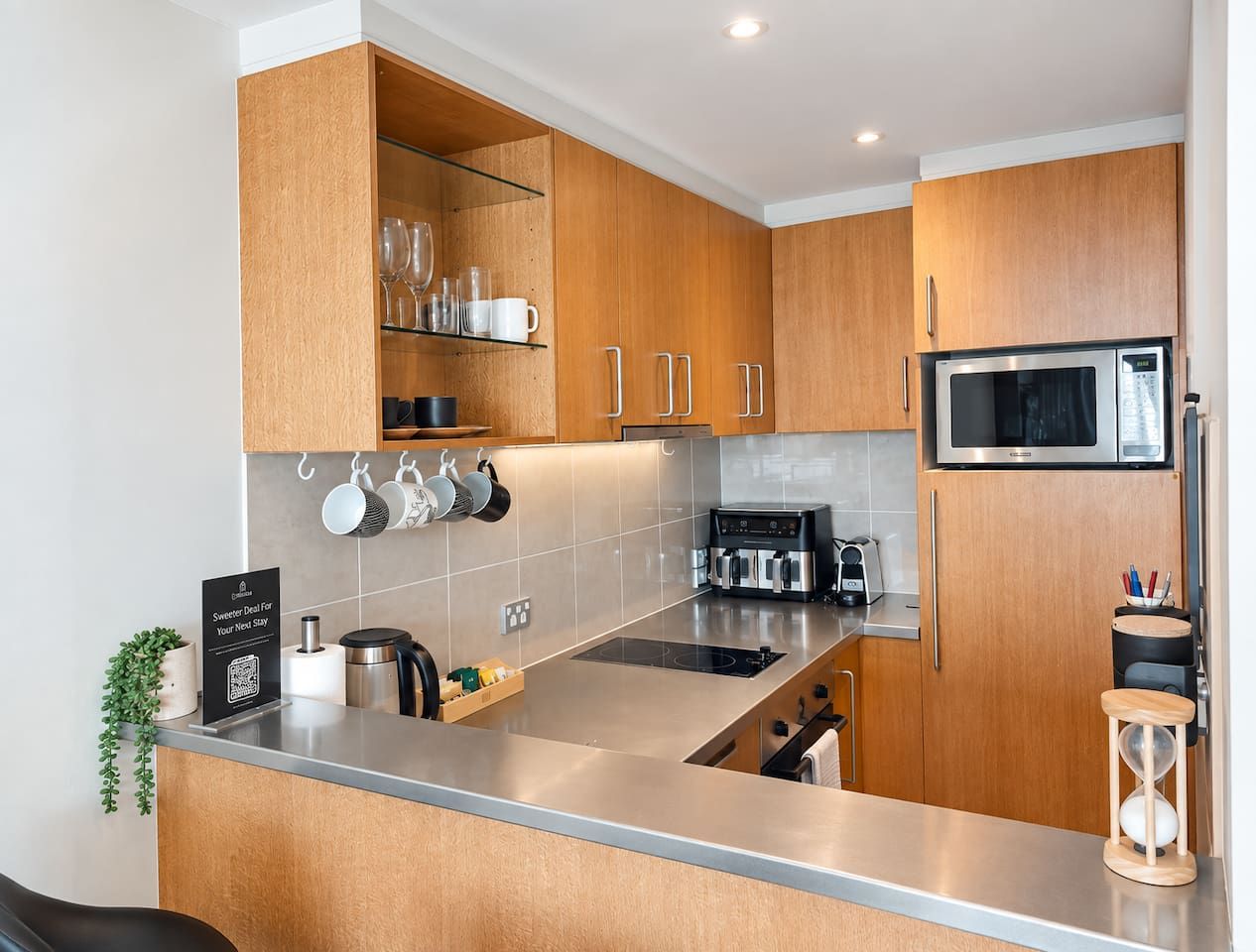 Una cocina moderna con armarios de madera, encimera de acero inoxidable y microondas integrado.