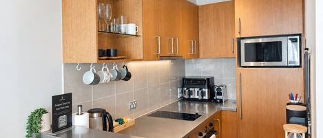 Una cocina moderna con armarios de madera, encimera de acero inoxidable y microondas integrado.