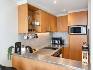 Eine moderne Küche mit Holzschränken, einer Edelstahl Arbeitsplatte und einer eingebauten Mikrowelle.
