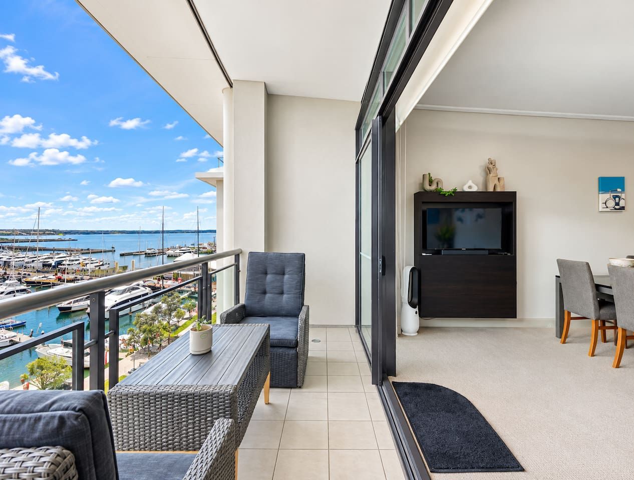 A balcony with a view of a marina, a dining area with a table and chairs, and a television.