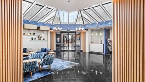 A modern lobby with a glass ceiling, a reception desk, and seating area. - Modern Harbourside 1BR w Balcony Zodiak Stays (Auckland City)