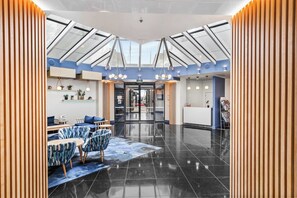 Eine moderne Lobby mit Glasdecke, einer Rezeption und einer Sitzgelegenheit.