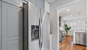 Eine moderne Küche mit einem Edelstahl-Kühlschrank, Holzboden und einem Blumentopf.