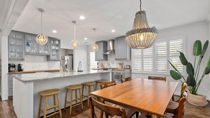 Eine moderne Küche mit einer zentralen Kochinsel, Holzbarhocker und Pendelleuchten.