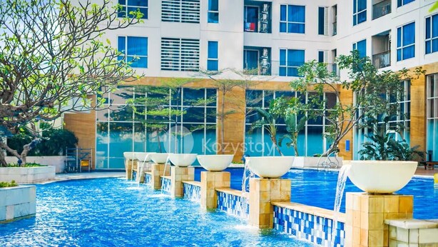 A swimming pool with multiple water features and a modern building in the background. - Nahara by Kozystay - Kuningan (Jakarta)