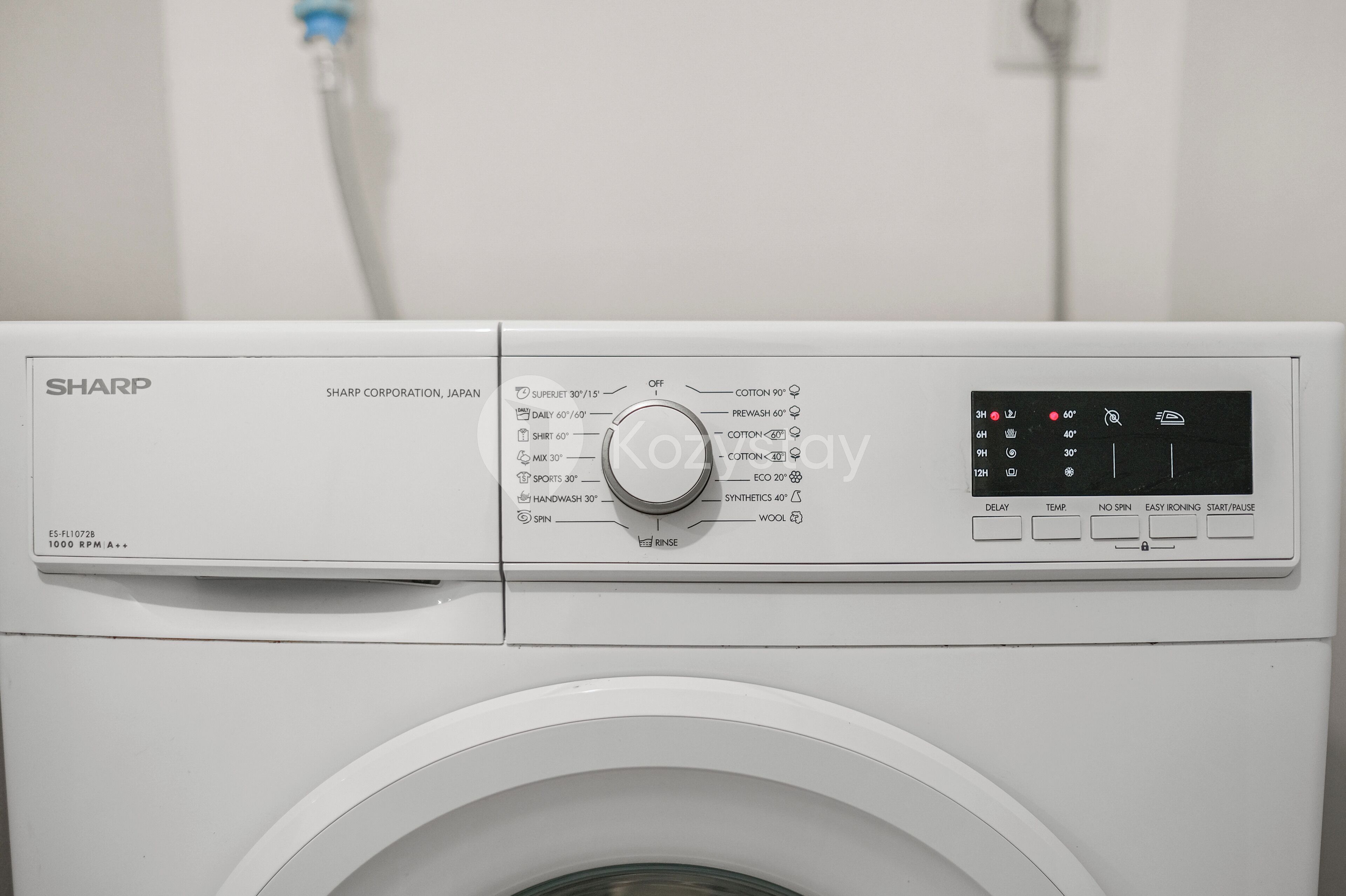 A white Sharp washing machine with a control panel displaying various settings and a digital display.