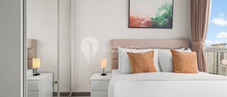 Una habitación de hotel moderna con una cama grande, dos mesitas de noche con lámparas, un espejo amplio y un cuadro abstracto enmarcado en la pared.