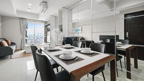 A modern dining area with a long table set for six, surrounded by chairs. - Nahara by Kozystay - Kuningan (Jakarta)