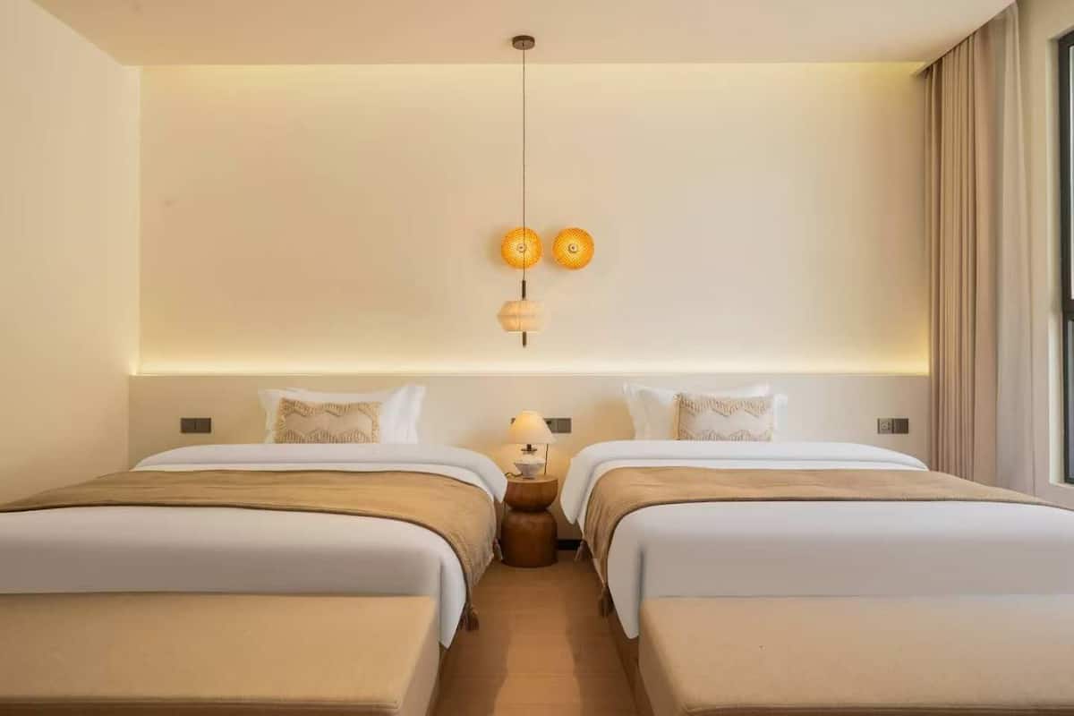 Ein Hotelzimmer mit zwei Betten, einem Nachttisch mit Lampe und einer Deckenleuchte.